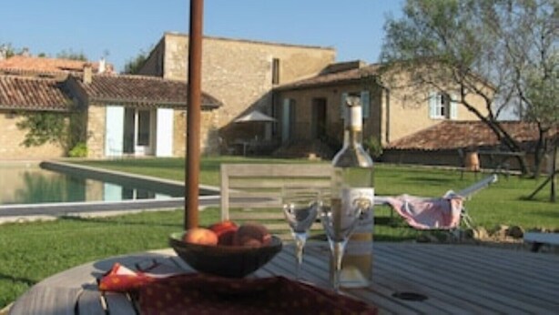A dining table with a bowl of fruit, a bottle, and a glass. - Architect's converted olive mill in historic town with garden and heated pool (Lorgues)