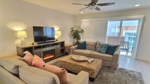 A living room with a fireplace, a television, a sofa, and a balcony with a view. - Frank's Pismo Beach House: Steps to Sand & Surf (Pismo Beach)