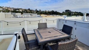 A rooftop terrace with a table and chairs, overlooking a residential area. - Frank's Pismo Beach House: Steps to Sand & Surf (Pismo Beach)