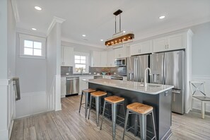 A modern kitchen with white cabinets, stainless steel appliances, and a central island with bar stools.