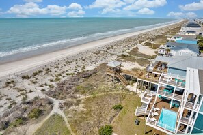 A beachfront property with a pool, multiple decks, and a beach view.