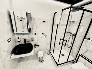 A modern bathroom with a glass-enclosed shower, a black sink, and a marble-tiled floor. - Castello Brancaccio  (San Gregorio da Sassola)