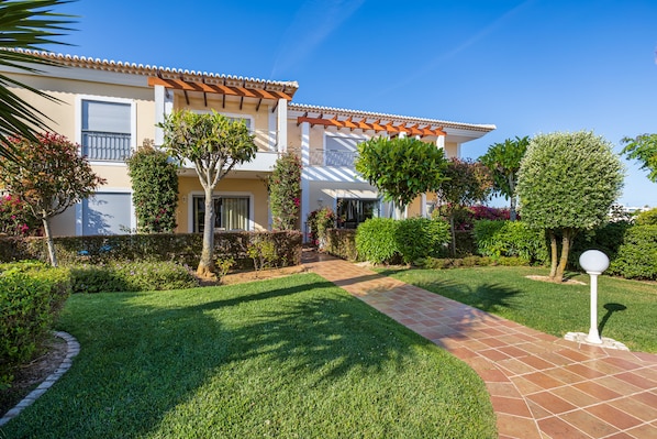 A house with a tiled roof, a paved pathway, and well-maintained gardens. - 3 bedroom apartment in Porto de mós, Lagos close to the beach (Lagos)