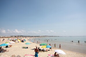 A beach with people sunbathing and swimming.