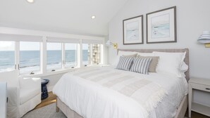 A bedroom with a large bed, a view of the sea, and two framed pictures on the wall. - Oceanfront 3BR/3Bath Premier Penthouse in the heart of Kiawah (Kiawah Island)