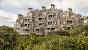 A multi-story building with a stone facade, multiple balconies, and a surrounding natural landscape. - Oceanfront 3BR/3Bath Premier Penthouse in the heart of Kiawah (Kiawah Island)