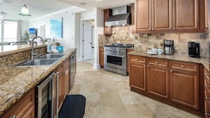 A modern kitchen with granite countertops, stainless steel appliances, and wooden cabinets. - BR 108: Golden Horizon - Indulge in the Ultimate Beachfront Escape! 2nd level (Fort Walton Beach)