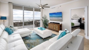 A spacious living room with a white sofa set, a coffee table, and a large flat-screen TV on the wall. - BR 108: Golden Horizon - Indulge in the Ultimate Beachfront Escape! 2nd level (Fort Walton Beach)