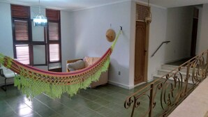 A living room with a hammock, a staircase, and a door. - conceitual hostel natal (Natal)