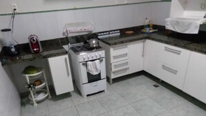 A compact kitchen with a gas stove, oven, and a small sink. There are white cabinets and a tiled backsplash. - conceitual hostel natal (Natal)