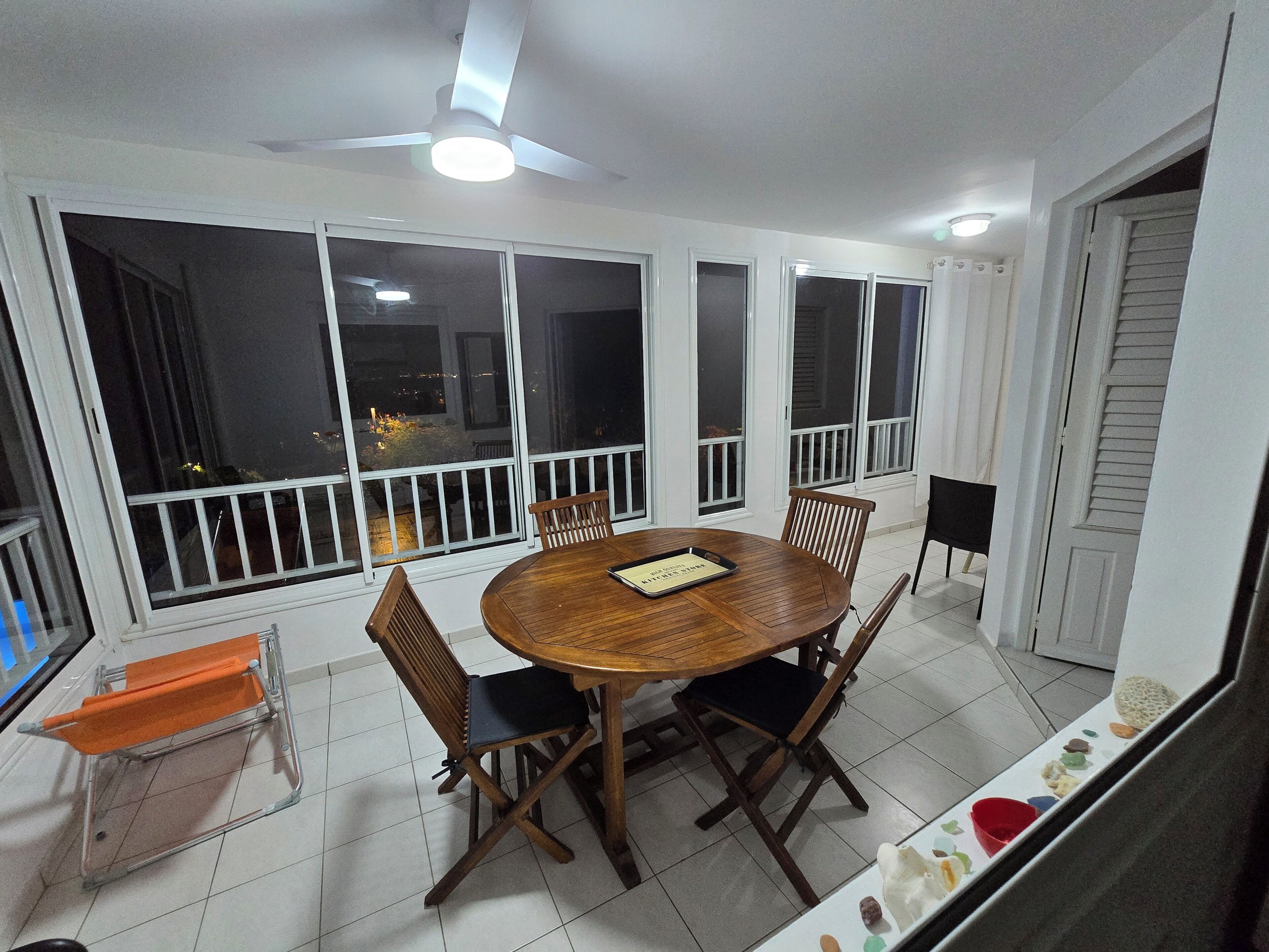 A dining area with a round table, chairs, and a ceiling fan.