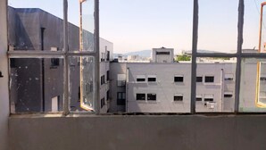 Una ventana con un diseño de cuadrícula, a través de la cual se distingue un conjunto de edificios.