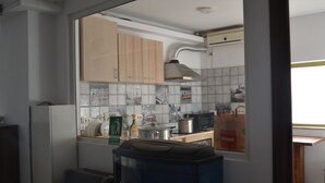 A compact kitchen with wooden cabinets, a built-in stove, and a window with a view of a building.
