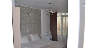 A bedroom with a large bed, a radiator, a nightstand, and a chandelier.