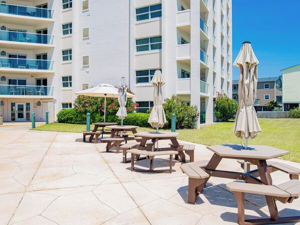 Un patio con mobiliario exterior y un edificio con varios balcones.