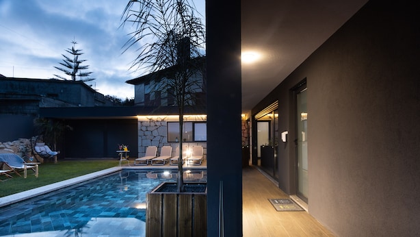 Un espace piscine extérieur moderne, agrémenté d’un mur en pierre, d’une terrasse en bois et de chaises longues.
