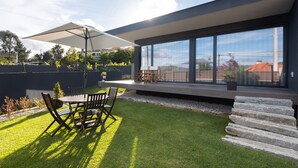 Une terrasse extérieure moderne, dotée d’une table et de chaises, d’un grand parasol et offrant une vue sur le quartier environnant.