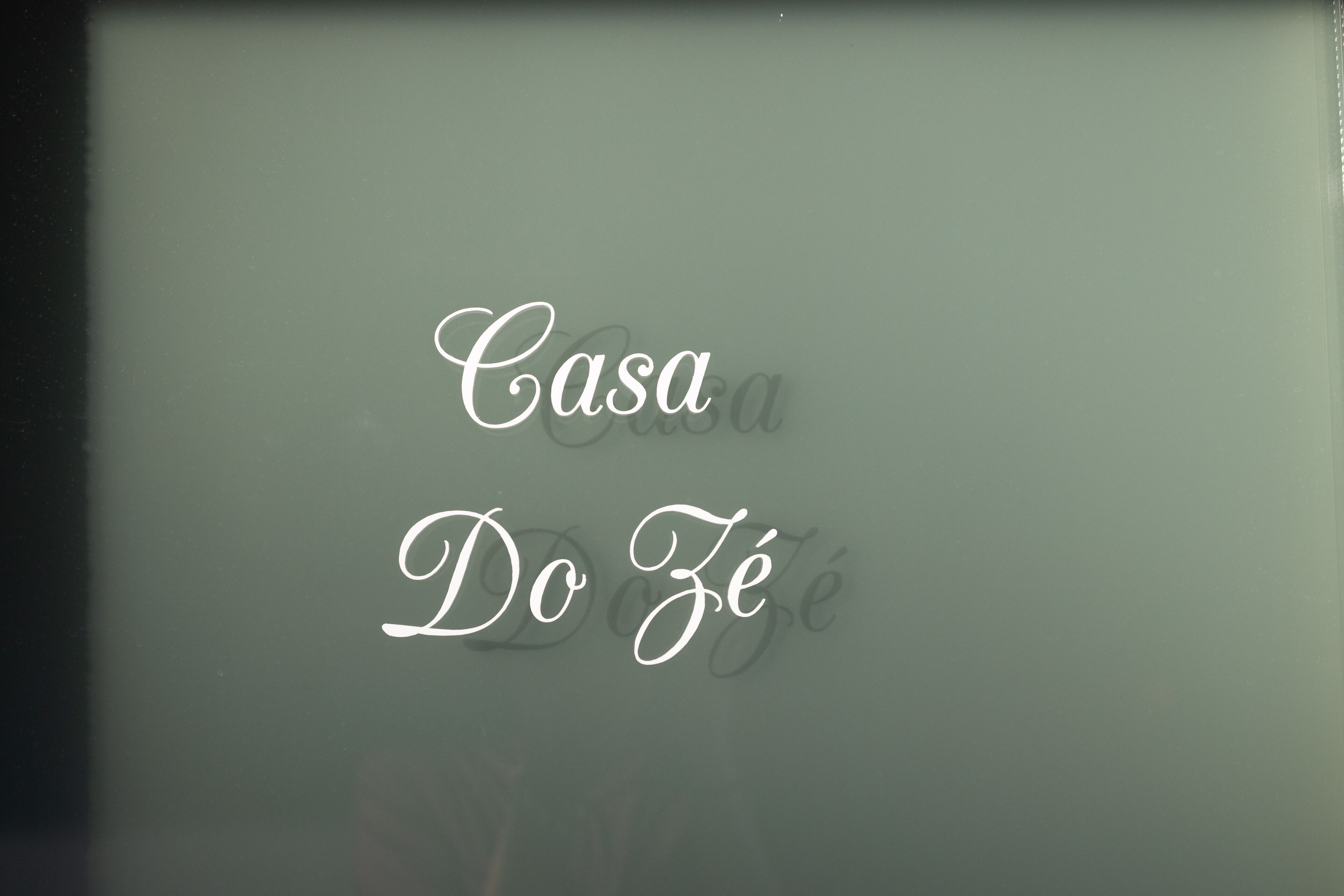 Ein Schild mit der Aufschrift 'Casa Do Zé' in kursiver Schrift.