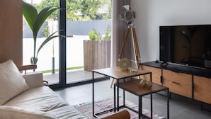 Un salon moderne avec un canapé, une table basse, un trépied et un téléviseur.