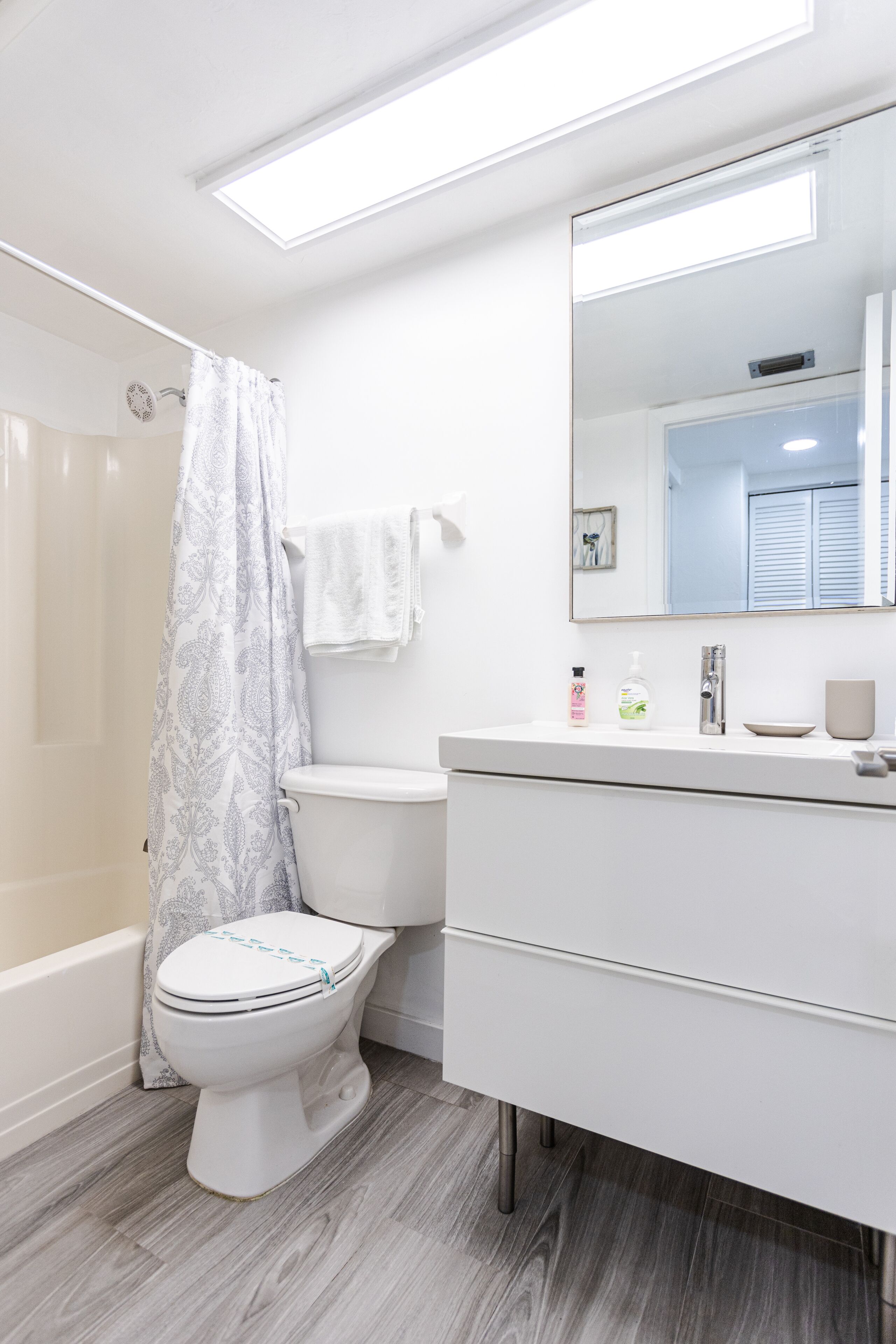 A modern bathroom with a toilet, shower, and vanity.