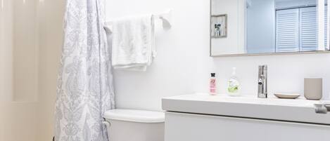 A modern bathroom with a toilet, shower, and vanity.