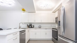 Una cocina moderna con armarios blancos, electrodomésticos de acero inoxidable y piso de madera clara.