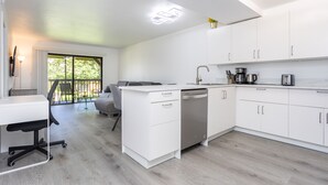 Una cocina moderna con armarios blancos, lavavajillas y cafetera.