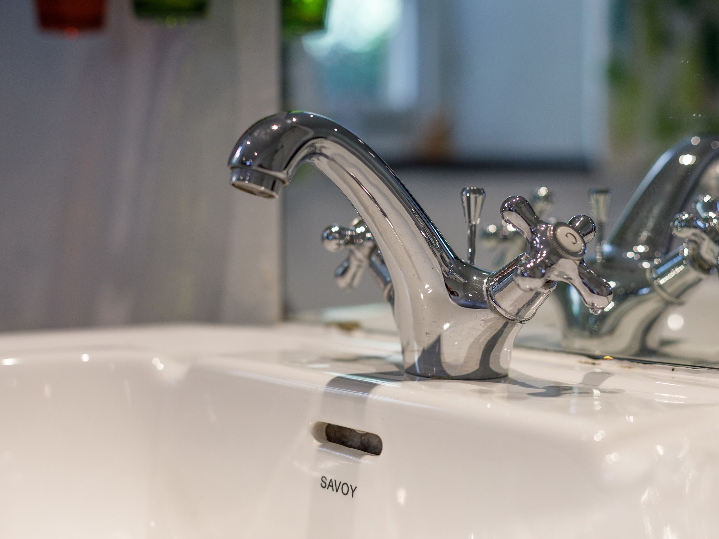 A modern bathroom sink with a single faucet and a visible brand name 'SAVOY'.