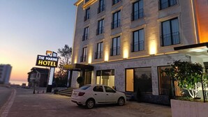 A hotel with a modern facade, multiple windows, and a sign indicating it is 'The Marine Hotel'. - The Marine Hotel  (Arsin)