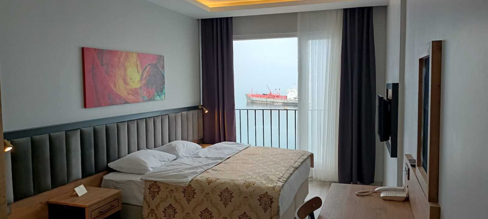 A hotel room with a bed, bedside table, and a painting on the wall.