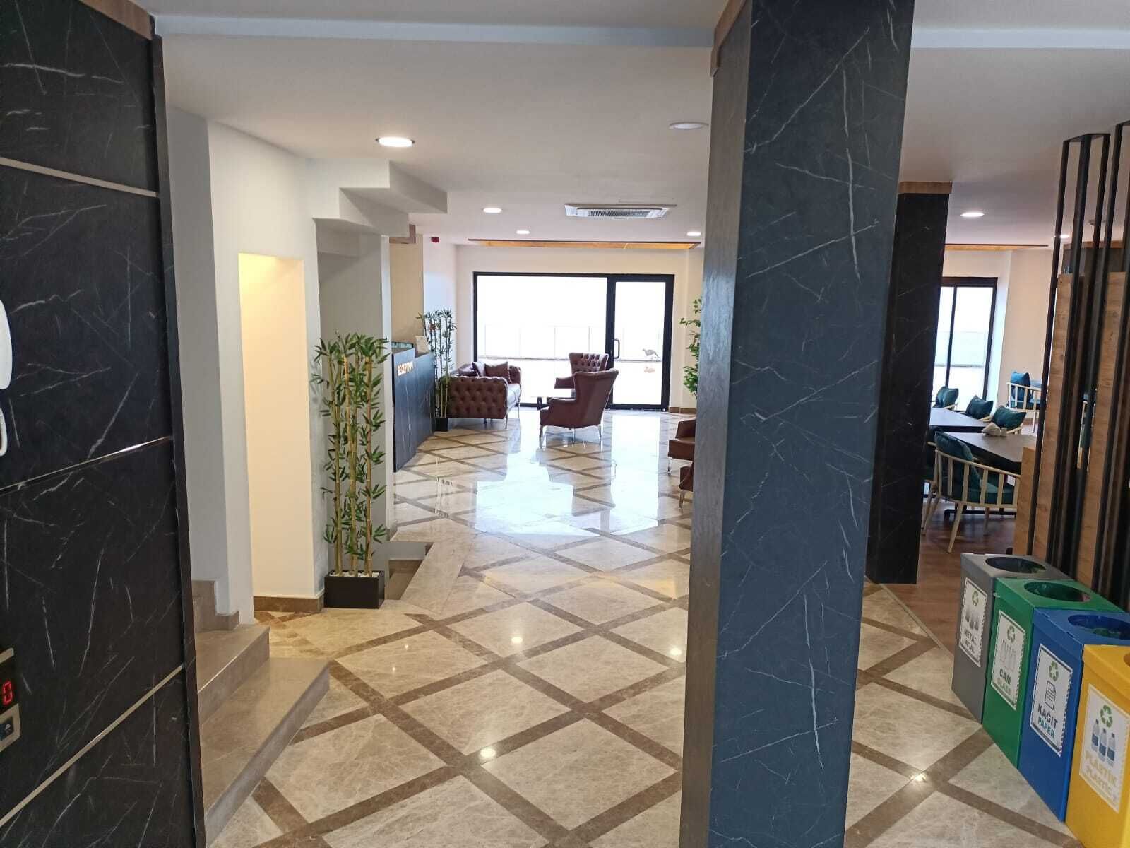 A hotel lobby with a reception desk, seating area, and recycling bins.
