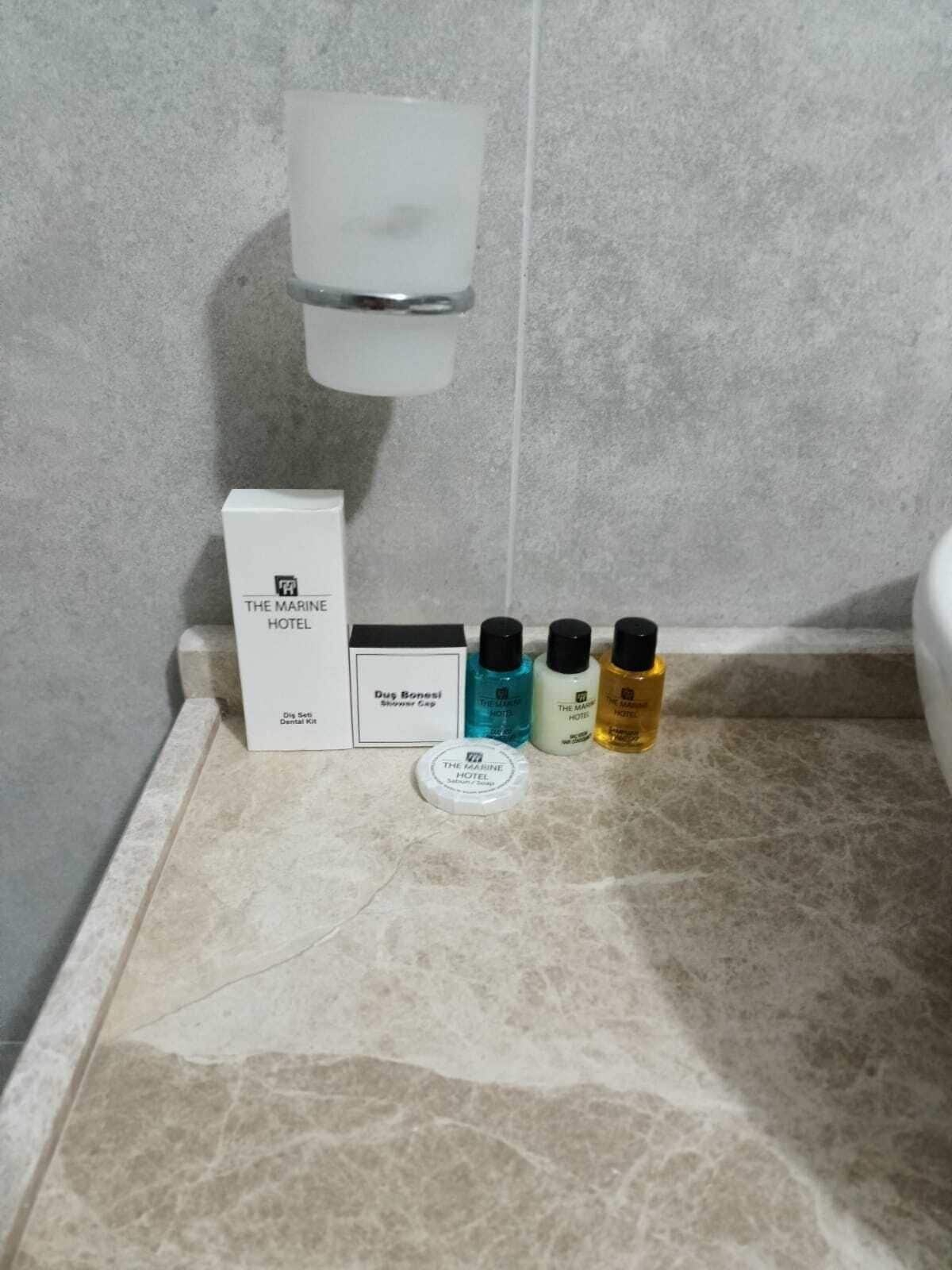 A bathroom with a marble countertop, a white soap dispenser, and four bottles of toiletries.