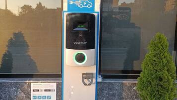 Une borne de recharge pour véhicules électriques VOLTRUN dotée d’un écran numérique, d’un indicateur de charge et d’un code QR pour accéder à des informations.