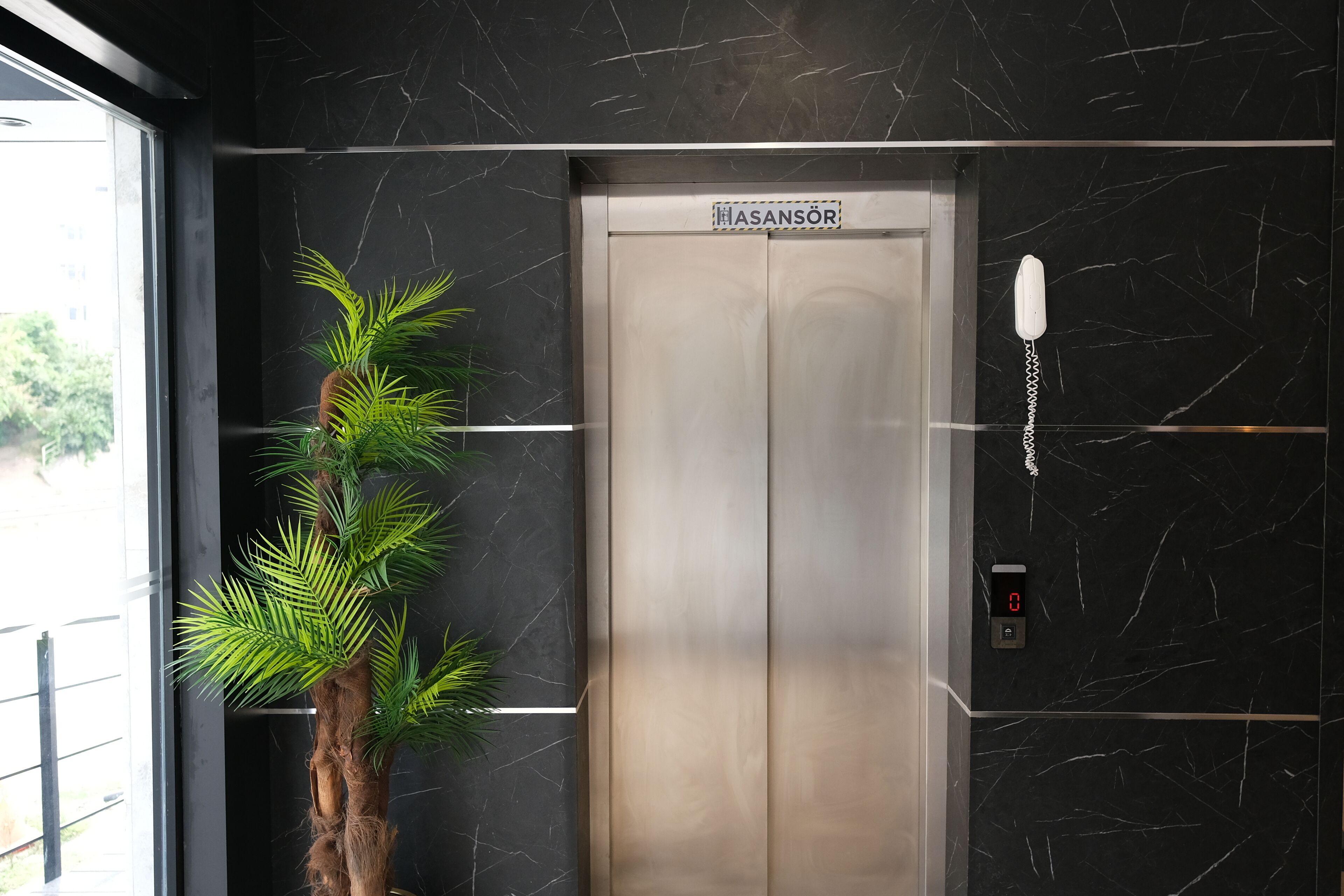 An elevator with a sign reading "HASANSÖR" and a phone on the wall.