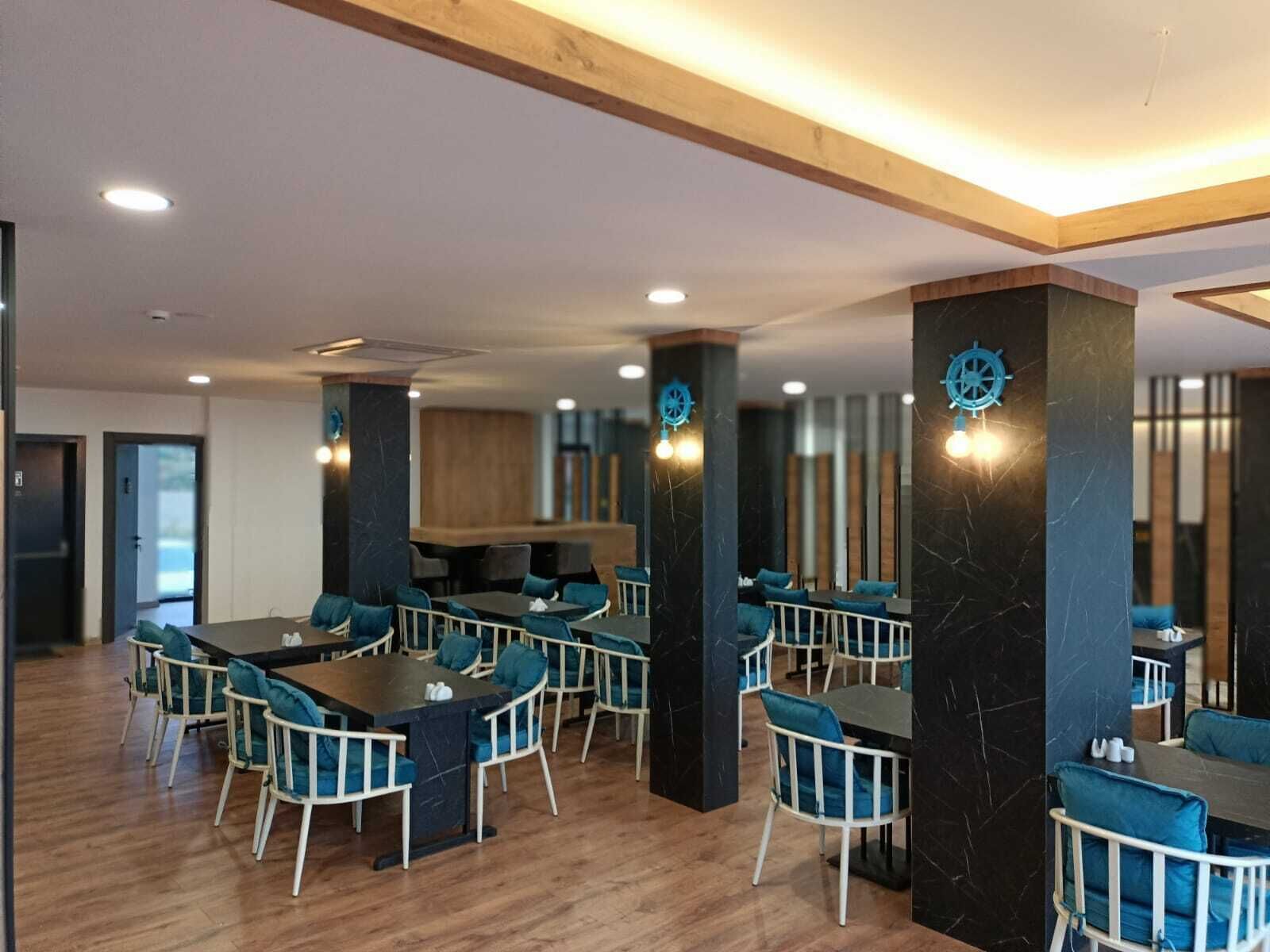 Un comedor moderno con suelo de madera, sillas tapizadas en azul y pilares de mármol oscuro.