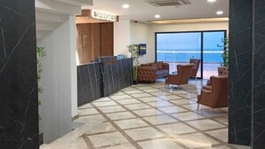 A reception area with a reception desk, seating area, and a view of the sea. - The Marine Hotel  (Arsin)