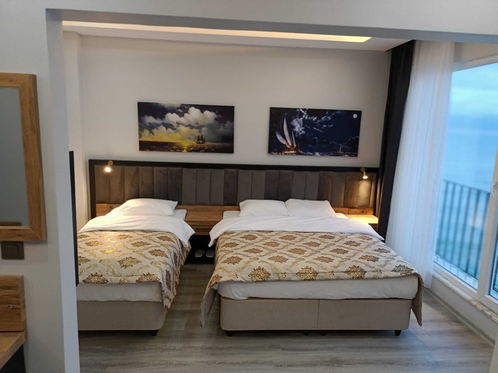 Habitación de hotel con dos camas, cabecero de madera y obras de arte en las paredes.