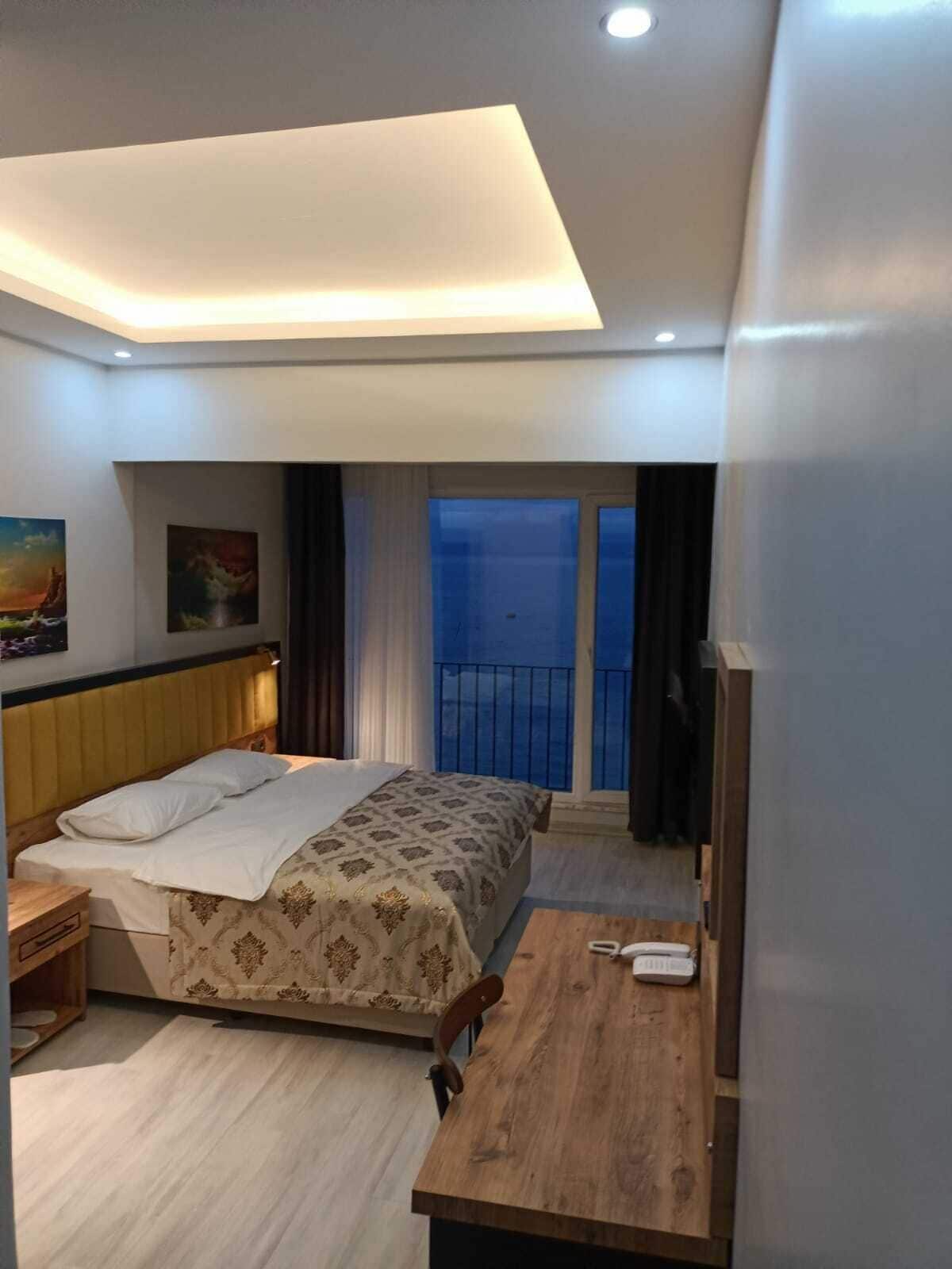 A hotel room with a bed, bedside table, and a view of the balcony.