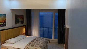 A hotel room with a bed, bedside table, and a view of the balcony.