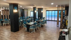A restaurant with multiple tables and chairs, large windows with a view of the sea, and a modern interior design. - The Marine Hotel  (Arsin)