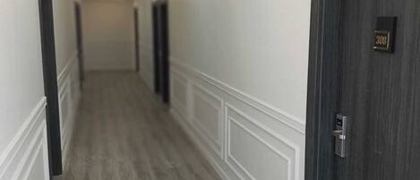 A hallway with a wooden floor, white wainscoting, and dark wooden doors.