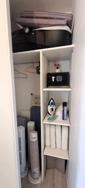 Um armário compacto com um cofre preto, um espaço para passar roupa pequeno e uma lata de tinta spray.