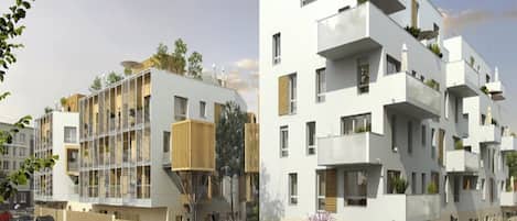 Un edificio residencial moderno con varios balcones, vista a la calle y automóviles estacionados.