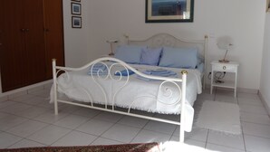 Ein Schlafzimmer mit Bett, Nachttisch, Lampe, Kleiderschrank und einem gerahmten Bild an der Wand.