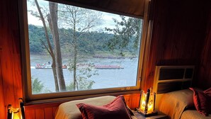 A room with a large window overlooking a river, two beds with pillows, and bedside lamps. - Costa del Sol Iguazú Nature, river & Jacuzzi (Puerto Iguazú)