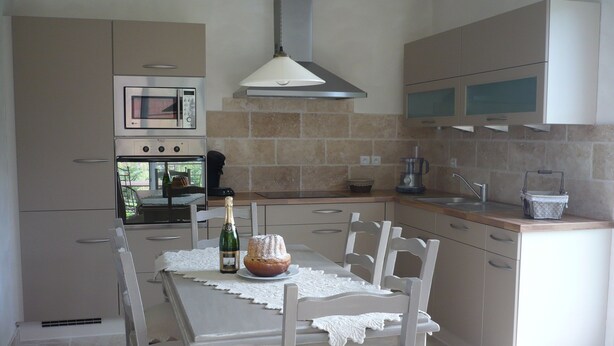Una cocina moderna con una mesa de comedor, sillas, una botella de champán y un pastel.