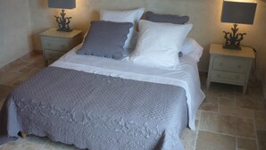 Un dormitorio con una cama, dos mesitas de noche y dos lámparas de pared.
