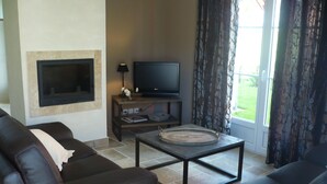 Una sala de estar con sofá, mesa de centro, televisor de pantalla plana y chimenea.