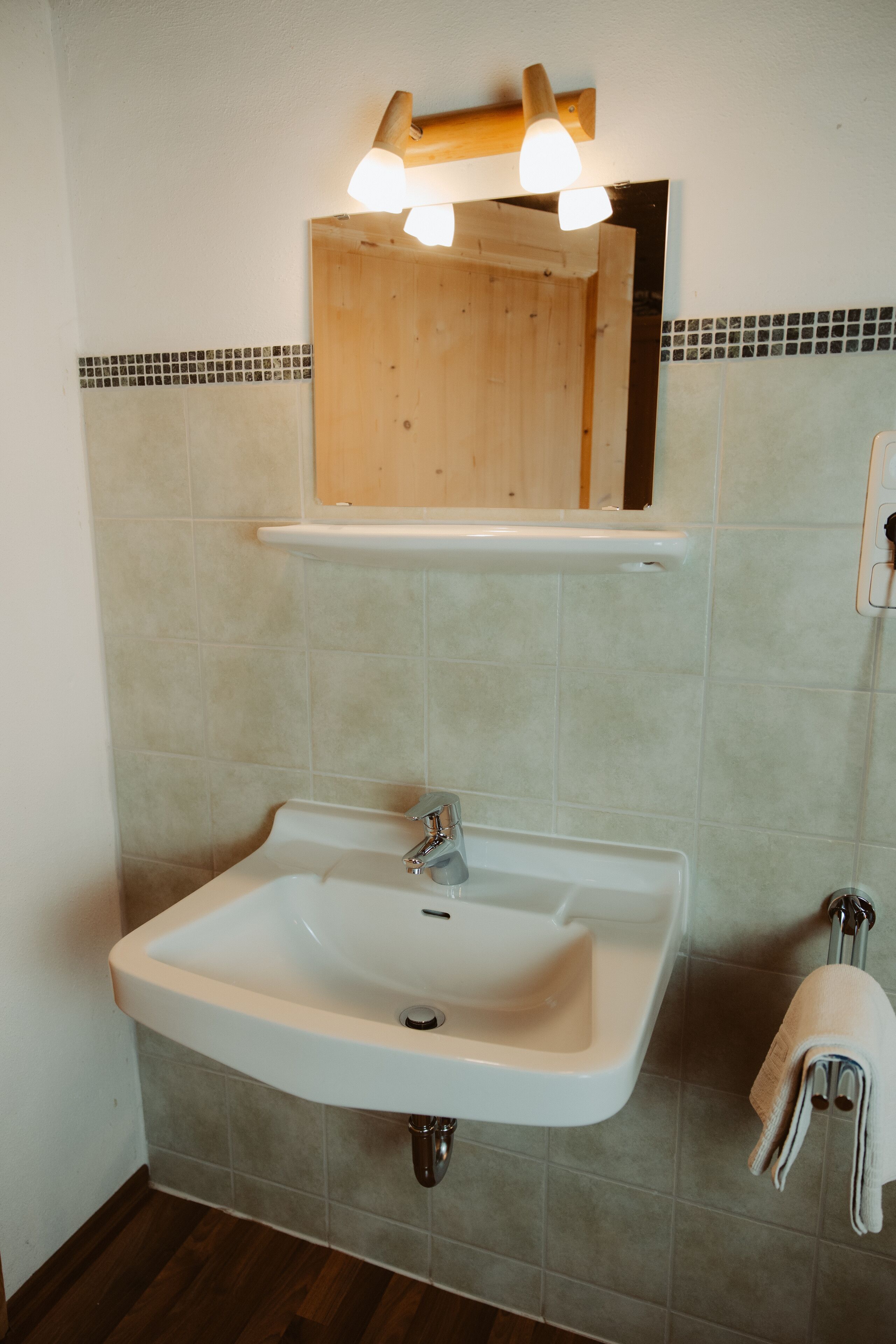 A bathroom with a white sink, a mirror, and a towel rack.