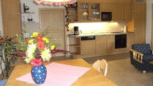 A kitchen with wooden cabinets, a microwave, and a coffee maker. There is a vase with flowers on the table.